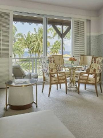 Helles Wohnzimmer mit Aussicht auf Palmen und Meer