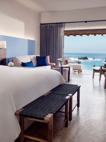 Zimmer mit Meerblick, einem großen Bett und stilvollen Holzmöbeln.