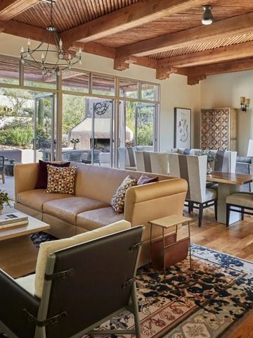 Geräumiger Wohnbereich in einem rustikalen Design mit Holzbalken und großen Fenstern.