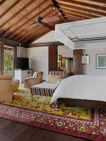 Geräumiges Zimmer mit Holzbalkendecke und Himmelbett im Resort auf den Seychellen