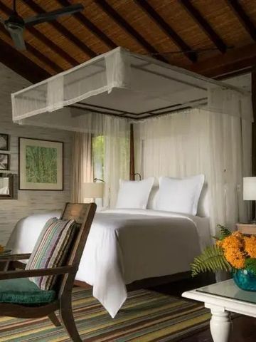 Gemütliches Schlafzimmer mit Himmelbett und klassischem Dekor im Four Seasons Resort Seychelles