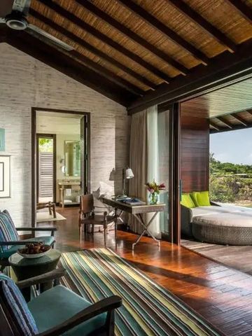 Modernes Zimmer mit offenem Zugang zur Terrasse und Blick ins Grüne im Resort auf den Seychellen