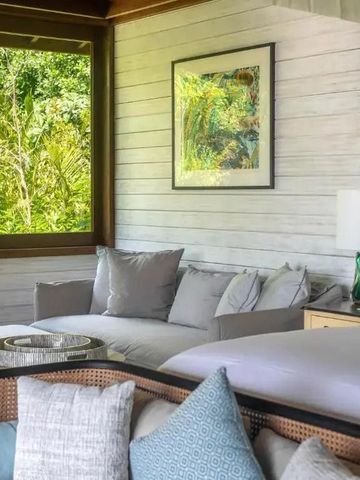 Behagliches Zimmer mit großem Fenster zum tropischen Garten und eleganten Möbeln