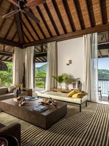 Großzügiger Wohnbereich mit exotischem Dekor und Zugang zu einem Balkon mit Blick auf den Ozean