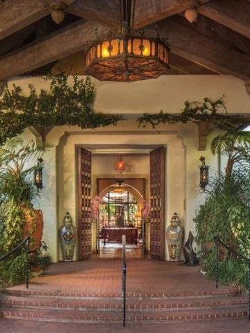 Entrance with open wooden doors surrounded by plants and rustic decor