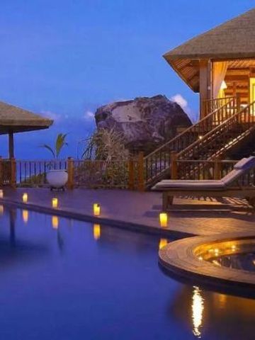 Villa am Infinity-Pool mit Aussicht auf das Meer im Abendlicht.