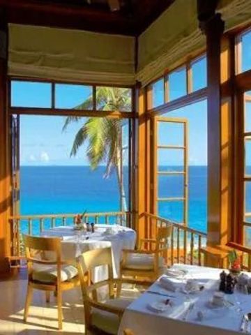 Restaurant mit Blick auf das Meer durch offene Fenster und Palmen im Hintergrund