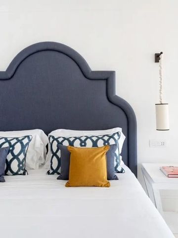 Hochwertiges Bett mit blauem Kopfteil und dekorativen Kissen im Hotelzimmer.