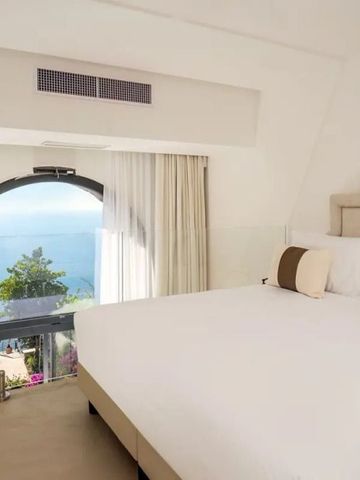Luxuriöses Schlafzimmer mit Panoramablick auf das Meer durch große Fenster.