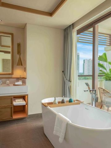 Elegantes Badezimmer mit freistehender Badewanne und Blick auf Terrasse mit Pflanzen