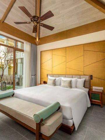 Helles Schlafzimmer mit großem Bett, Sesseln und Zugang zu privatem Poolbereich