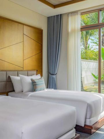 Doppelzimmer mit zwei Einzelbetten und großem Fenster, das auf einen kleinen Garten blickt