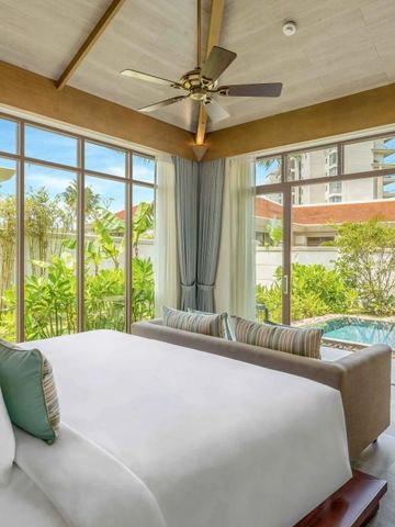 Geräumiges Schlafzimmer mit großem Bett, Sofaecke und Blick auf den Pool