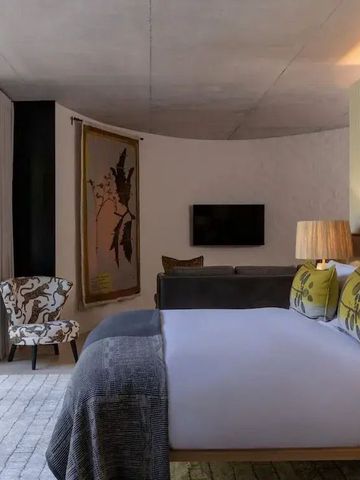 Modernes Schlafzimmer mit Designer-Stuhl und großem Bett.