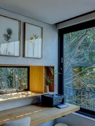 Modern eingerichteter Arbeitsbereich mit Blick auf den Wald durch ein großes Fenster