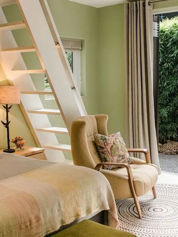 Elegantes Schlafzimmer mit Leiter zum Hochbett und offenem Zugang zum Garten