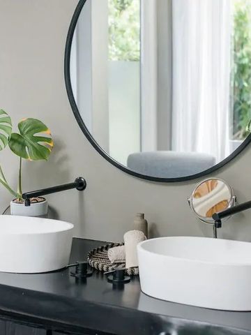 Modernes Badezimmer mit doppeltem Waschbecken und runden Spiegel