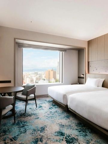 Hotelzimmer mit zwei Einzelbetten und Stadtblick durch großes Fenster