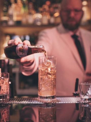 Elegante Hotelbar mit Barkeeper im Anzug der ein Getränk ausschenkt