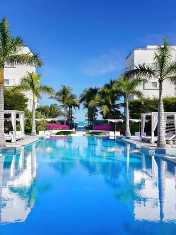 Infinity-Pool mit Palmen und Meerblick zwischen weißen Gebäuden