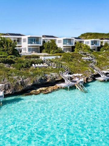 Villen an einer Klippe über türkisfarbenem Wasser mit Treppen zum Meer