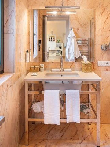 Marmorbadezimmer mit großem Spiegel und Handtüchern auf Ablage