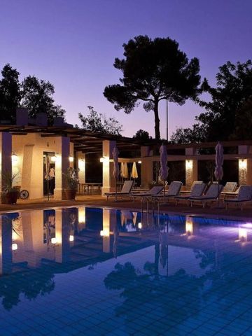 Beleuchteter Pool bei Dämmerung mit Liegestühlen und Bäumen im Hintergrund
