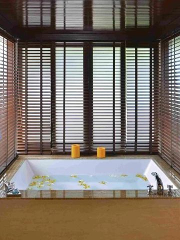 Luxuriöse Badewanne mit Blüten und weichen Bademänteln