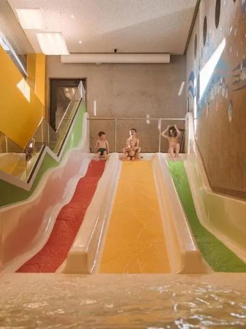 Innenbereich mit bunten Wasserrutschen und Kindern beim Spielen