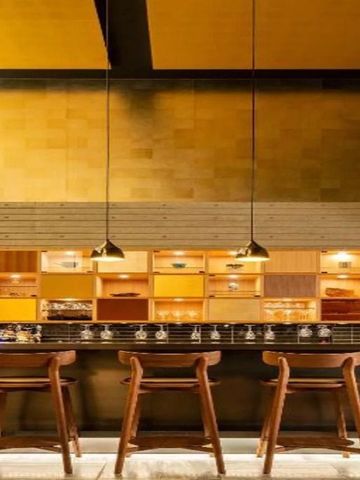 Elegante Bar mit dezenter Beleuchtung und stilvollen Hockern aus Holz