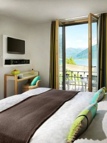 Helles Hotelzimmer mit Balkonblick auf den See und die Berge