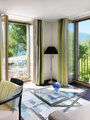 Gemütlicher Sitzbereich in einer Hotelsuite mit Balkon und Seeblick