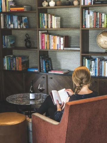 Gemütliche Leseecke in der Lodge mit Bücherregal und Glas Wein