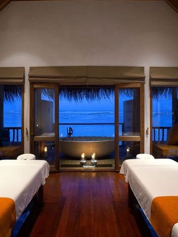 Spa mit Kerzen und zwei Massageliegen Blick auf das Meer bei Abenddämmerung