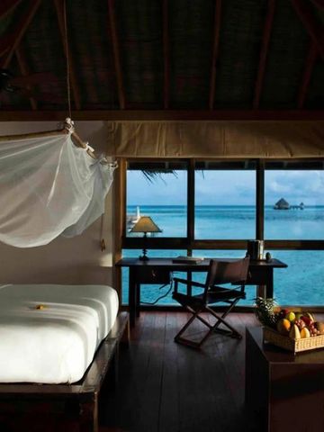 Elegantes Schlafzimmer mit Moskitonetz und Blick aufs türkisblaue Meer