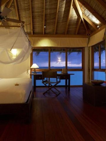 Helles Schlafzimmer mit Holzdach und Panoramablick aufs Meer