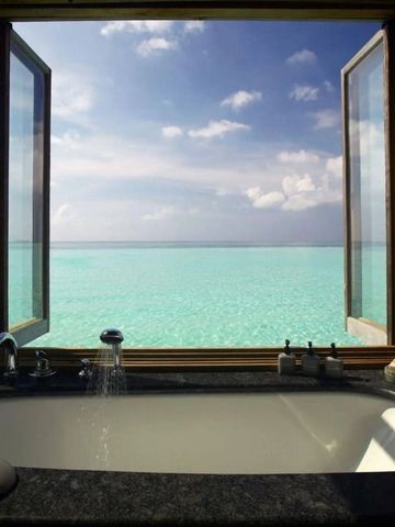 Blick aus einem Badezimmerfenster auf das türkisblaue Meer