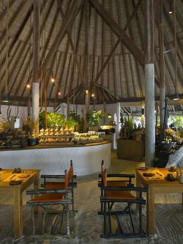 Restaurant im Freien mit strohgedecktem Dach und eleganter Holzeinrichtung