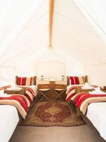 Großes Zelt mit mehreren Betten und traditionellen Teppichen.