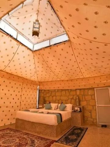 Innenansicht eines aufwendig gestalteten Safari-Zeltes mit Bett und Laterne