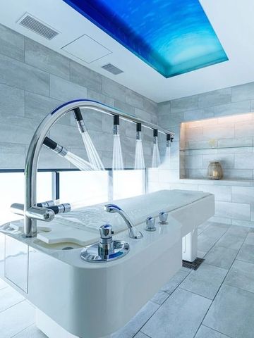 Moderner Spa-Raum mit Wasserfall-Dusche und ambienter Beleuchtung an der Decke.