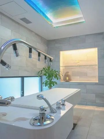 Spa-Raum mit Wasserfall-Dusche und beruhigender blauer Deckenbeleuchtung.