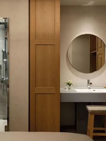 Stilvolles Badezimmer mit rundem Spiegel und moderner Dusche in Holzakzenten.