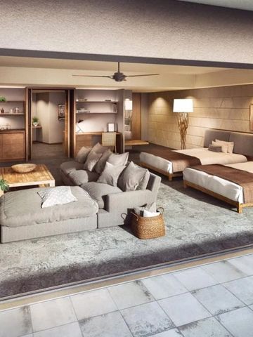 Geräumige Suite mit gemütlicher Sitzecke und zwei Betten in warmen Farbtönen.