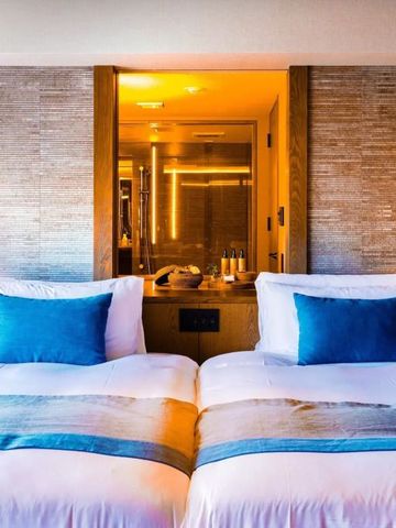 Doppelbettzimmer mit stilvollem Beleuchtungskonzept und luxuriösen Details.