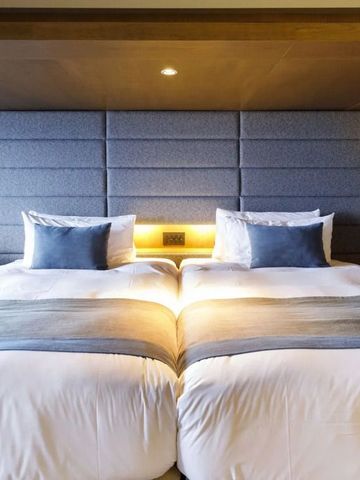 Modernes Hotelzimmer mit zwei großen Betten und eleganter Beleuchtung