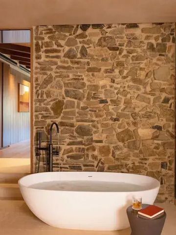 Freistehende Badewanne vor einer rustikalen Steinwand