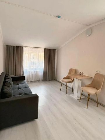 Helles Zimmer mit Sofa, Tisch und Stühlen, neutraler Einrichtung.