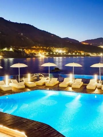 Beleuchteter Pool mit Liegen und Schirmen bei Nacht mit Meerblick