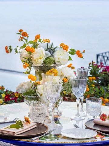 Tisch mit Blumenarrangement und Geschirr mit Meerblick.